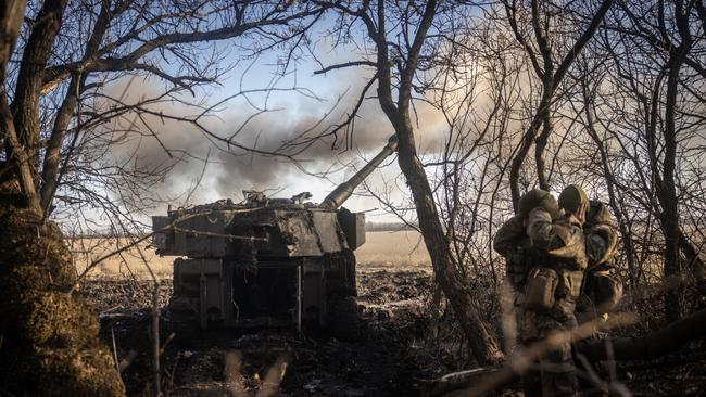 Members of a Ukrainian artillery unit cover their ears as an M109 self propelled artillery unit is fired at Russian mortar positions around Vuhledar.