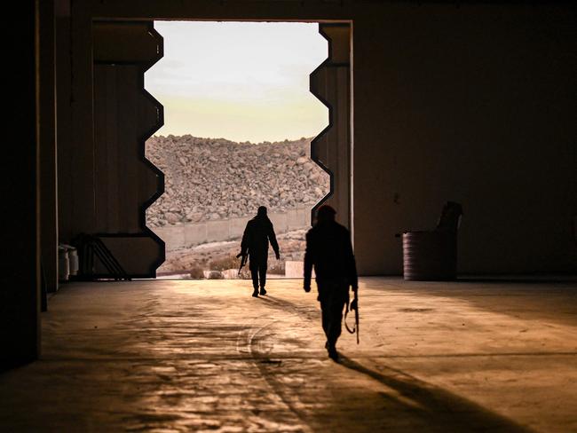 Syrian rebel fighters search the warehouse of a drug manufacturing facility that was producing pills of Captagon, a brand name of the drug psychostimulant Fenethylline, in the city of Douma in the Eastern Ghouta region on the eastern outskirts of Damascus on December 12, 2024. The dramatic collapse of Bashar al-Assad's Syrian regime has thrown light into many of the dark corners of his rule, including the industrial-scale export of the banned drug Captagon. Victorious Islamist fighters have seized military bases and distribution hubs for the amphetamine-laced stimulant, which has flooded the black market across the Middle East. (Photo by Aris MESSINIS / AFP)