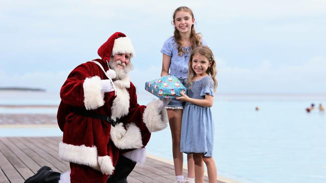 Bruce Skilbeck has been playing Santa Claus at DFO Shopping Centre this year, spreading the joy of the Christmas season to the young and the young at heart. Santa, aka Bruce Skilbeck, gifts a Christmas present to his grand daughters Lilly Hogan, 11, and Grace Hogan, 5, at the Esplanade Lagoon. Picture: Brendan Radke