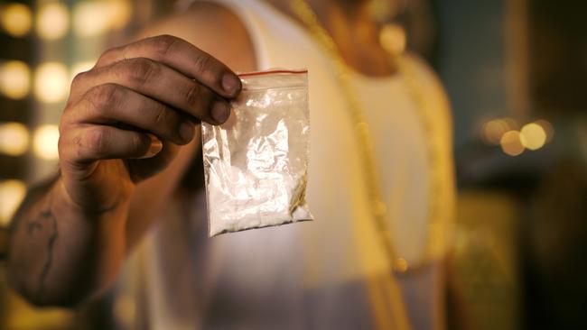 Brutal Drug Dealer Wearing Sleeveless Shirt and Gold Chain Holds and Offers Sample Bag Full of Drugs. He Lives in the Abandoned Building with Boarded Up Windows.