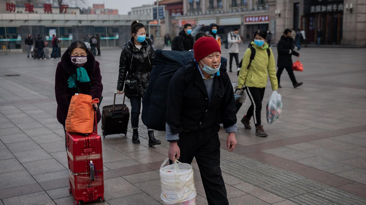 People wear protective masks to help stop the spread of a deadly virus which began in Wuhan, queue to take a taxi at the Beijing railway station. Picture: AFP