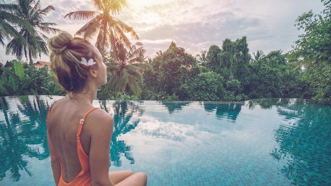 Young woman standing on the edge of an infinity pool, Ubud, Bali People travel vacations concept.