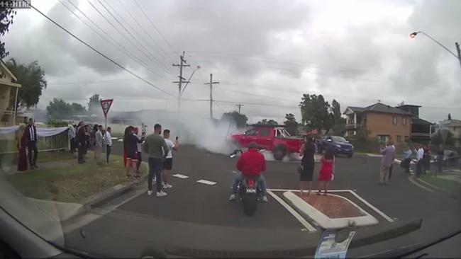 Bystanders and wedding guests are seen filming the burnouts on the blocked off roundabout. Picture: Facebook/Dash Cam Owners Australia