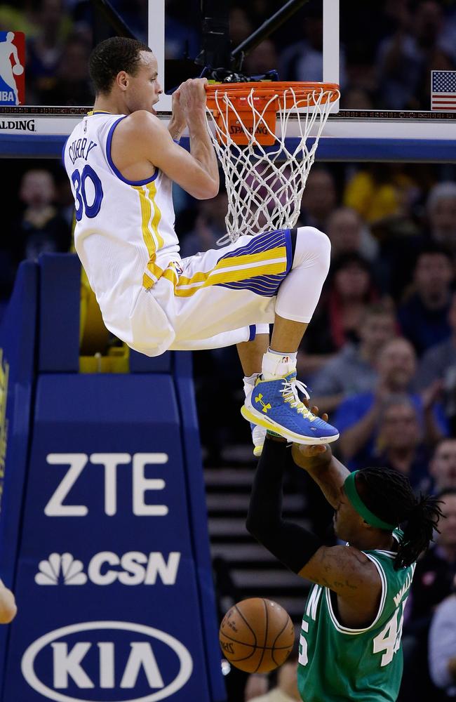 Golden State’s Stephen Curry hangs on the rim after dunking the ball on Gerald Wallace.