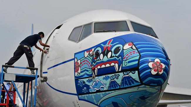 A worker closes a door of a Garuda Indonesia Boeing 373-800 NG with a new face mask design as part of a campaign to promote the wearing of face masks amid the COVID-19 coronavirus. Picture: AFP