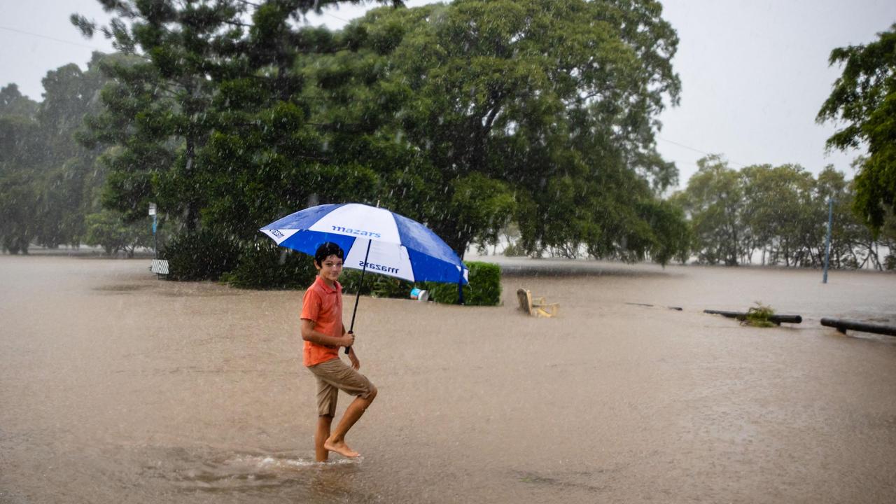 A child wades through a waterlogged street on the banks of the overflowing Brisbane River. Picture: Patrick Hamilton/AFP