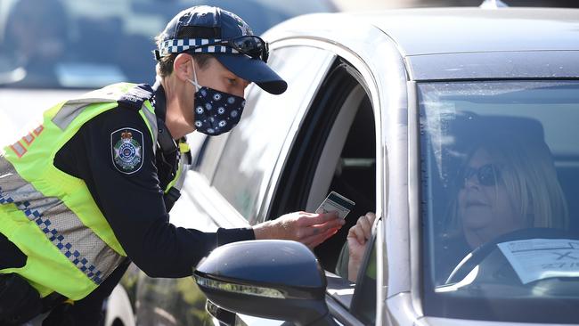 A Queensland Police Service officer inspecting a motorist’s documentation at the Queensland-NSW border. Picture: Matt Roberts/Getty Images