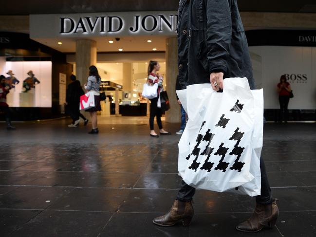 A customer carries a shopping bag featuring the houndstooth branding of David Jones Ltd. as she walks past the company's Bourke Street store in Melbourne, Australia, on Wednesday, April 9, 2014. South Africa's Woolworths Holdings Ltd. agreed to buy Australian retailer David Jones Ltd. for A$2.15 billion ($2 billion) to expand in a market targeted by global rivals including Inditex SA and Hennes & Mauritz AB. Photographer: Carla Gottgens/Bloomberg