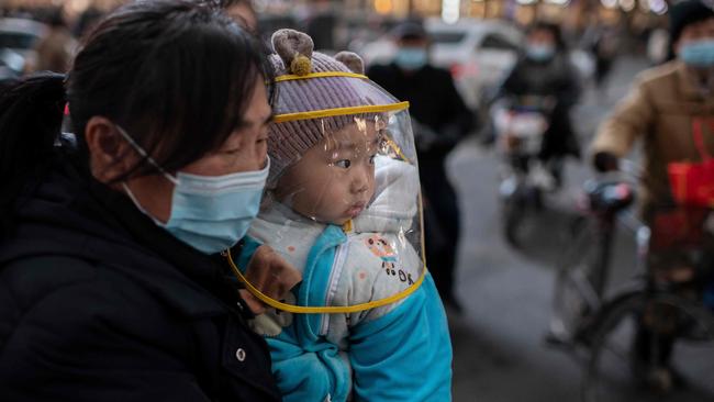 A woman holds a baby during rush hour in Wuhan. Picture: AFP