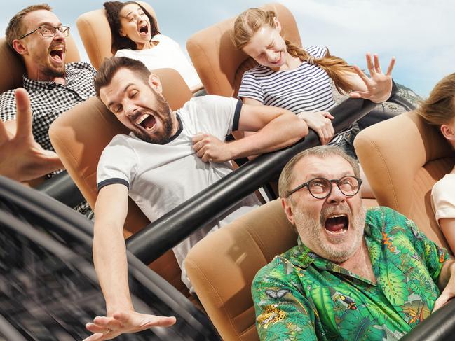 Speed doesn't stop, enjoy it. Emotional people on the roller coaster going down wih meadows on background. Caucasian men and women get adrenaline activity and having fun together on the rides.