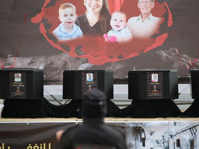 The coffins of the four Israeli hostages sit on stage during the handing them over to the Red Cross in Khan Yunis in the southern Gaza on February 20, 2025. Hamas handed over on February 20 coffins believed to contain the bodies of four Israeli hostages, including those of the Bibas family who became symbols of the ordeal that has gripped Israel since the Gaza war began. (Photo by Eyad BABA / AFP)