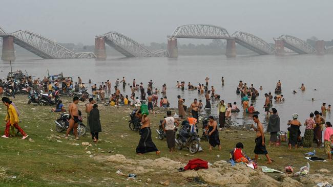 People bathe in the Irrawaddy River near the collapsed Ava Bridge with much of Myanmar still without electricity or water. Picture: AFP