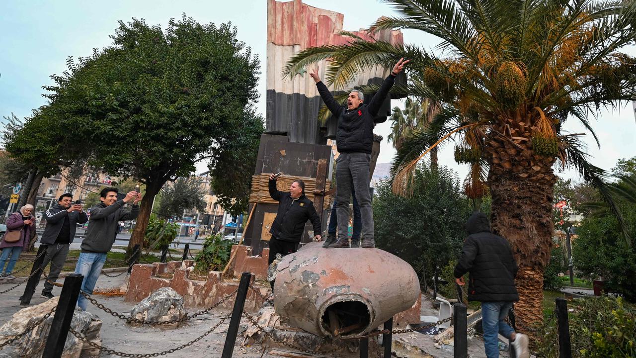 People stand atop a toppled statue of Syria’s late president Hafez al-Assad in Damascus. Picture: Louai Beshara/AFP