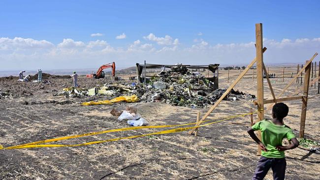 A boys look as forensic investigators comb the ground for DNA evidence near a pile of twisted airplane debris at the crash site at Hama Quntushele village. Picture: AFP