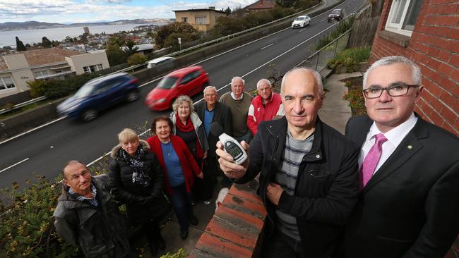 Resident Simon Wright, left front, measures the sound level next to the Southern Outlet as Denison MHR Andrew Wilkie, right front, and other Dynnyrne residents lend support. Picture: CHRIS KIDD