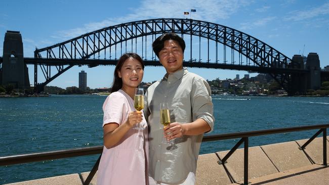 SYDNEY, AUSTRALIA : NewsWire Photos - DECEMBER 23 2024; Korean couple on their honeymoon Selugi Kim and Kyeongwon Lee pose for a photo at the Opera House forecourt with a view of the Sydney Harbour Bridge in the background as new tourism data for NSW is released. Picture: NewsWire/ Gaye Gerard