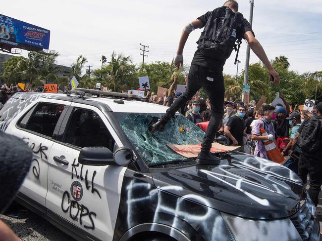 TOPSHOT - Demonstrators smash a police vehicle in the Fairfax District as they protest the death of George Floyd,  in Los Angeles, California on May 30, 2020. - Demonstrations are being held across the US after George Floyd died in police custody on May 25. (Photo by Mark RALSTON / AFP)