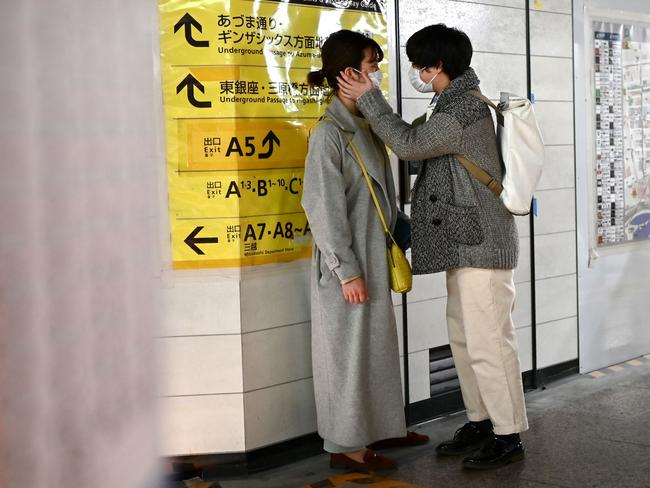 A couple wearing face masks, amid concerns of the COVID-19 coronavirus, chat at a train station in Tokyo.