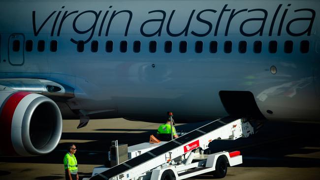 Baggage handlers prepare to unload freight from a Virgin Australia aircraft on the tarmac at Brisbane International airport on April 21. Picture: Patrick Hamilton/AFP.