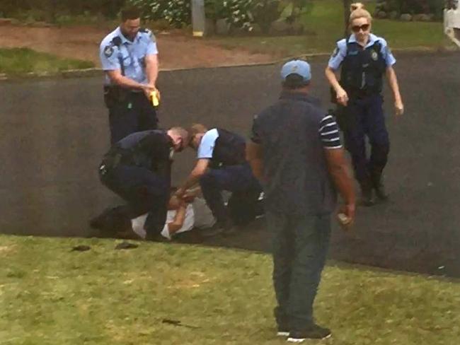 NSW Police officers restrain Ihsas Khan. The knife can be seen on the grass / Picture supplied