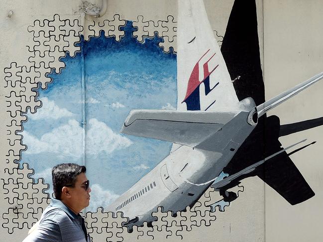 A Malaysian man walking in front of a mural of missing Malaysia Airlines MH370. The disappearance of the Boeing 777 carrying 239 passengers and crew almost four years ago is one of aviation's greatest mysteries. Picture: AFP