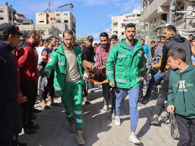 People gather as rescuers transport a casualty pulled from the rubble of a house destroyed in an Israeli strike on al-Jalaa street in central Gaza City. Picture: AFP