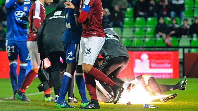 A firecracker explodes beside Lyon and Metz players.