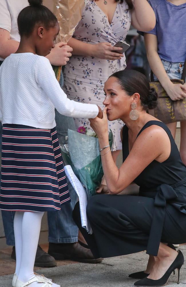 Meghan, Duchess of Sussex, kisses the hand of a young girl outside mothers2mothers in Cape Town. Picture: Matrix.