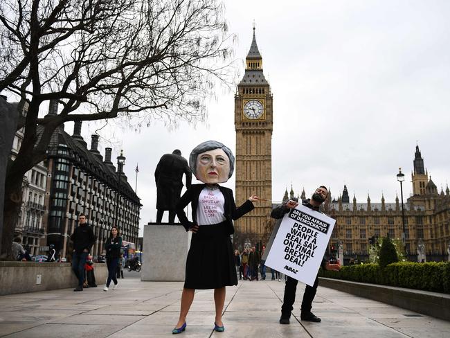 A demonstrator wearing a mask depicting Britain's Prime Minister Theresa May, protests against the United Kingdom's triggering of Article 50, outside the Houses of Parliament in central London on March 29, 2017. British Prime Minister Theresa May will formally launch Brexit today after signing the letter to begin the country's departure from the European Union. / AFP PHOTO / Justin TALLIS