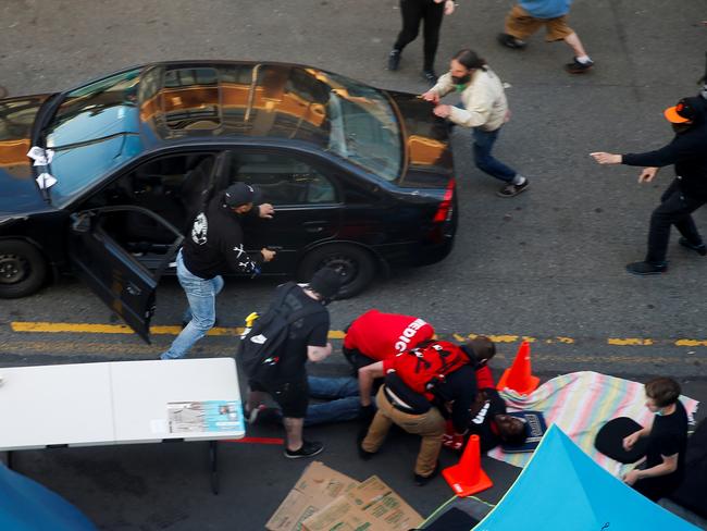 A man exits a vehicle with a gun as a man is tended to by medics after being shot by a driver in Seattle. Picture: Reuters