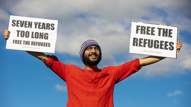 Greens Councillor Jonathan Sri holds signs to support asylum seekers detained at the Kangaroo Point Central Hotel in Brisbane, Sunday, June 21, 2020. (AAP Image/Glenn Hunt) NO ARCHIVING