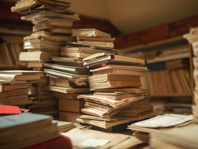 Library with archive of very old books and documents stored and unsorted. Big mess that looks beautiful.