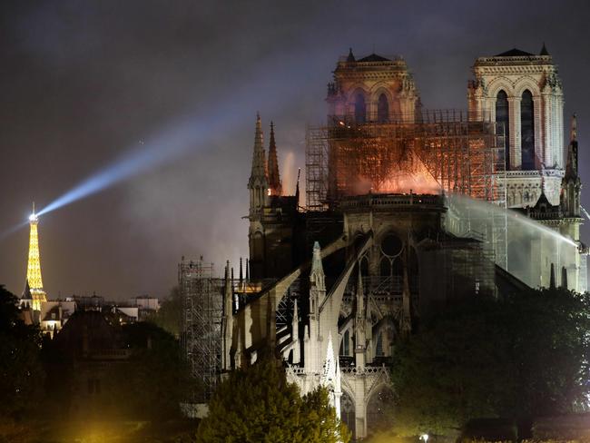 Firefighters douse flames billowing from the roof at Notre-Dame Cathedral in Paris on April 15, 2019. - A colossal fire swept through the famed Notre-Dame Cathedral in central Paris causing the spire to collapse and raising fears over the future of the nearly millenium old building and its precious artworks. The fire, which began in the early evening, sent flames and huge clouds of grey smoke billowing into the Paris sky as stunned Parisians and tourists watched on in sheer horror. (Photo by LUDOVIC MARIN / AFP)