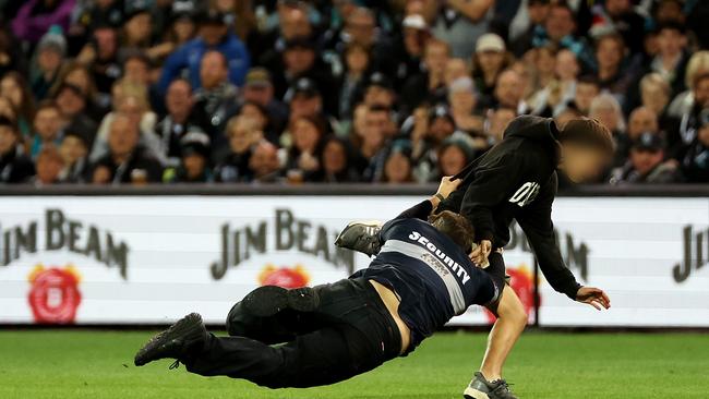 A pitch invader is tackled by security at Adelaide Oval during the round three Showdown between Port Adelaide. Picture: Mark Brake / Getty Images