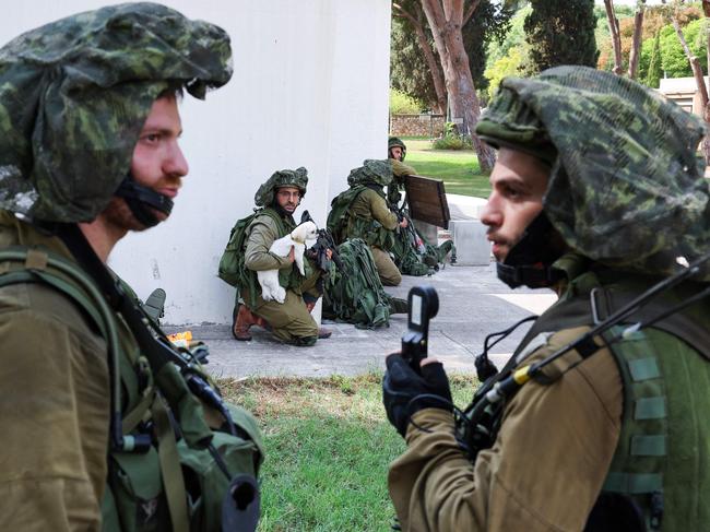 An Israeli soldier holds a dog as his unit take position in Kfar Aza, in the south of Israel, bordering Gaza Strip. Picture: AFP