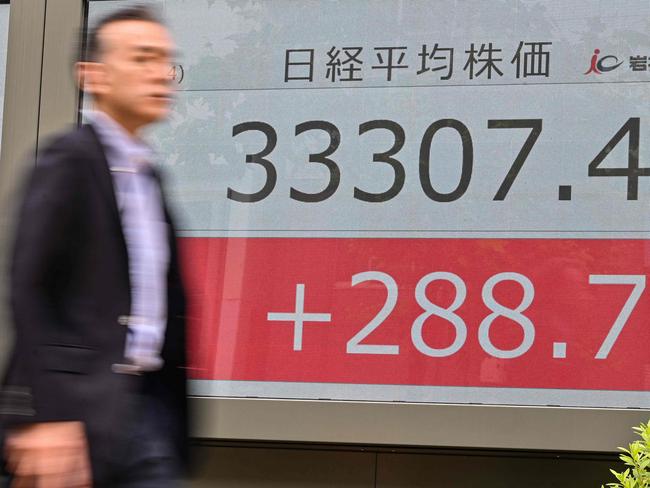 A man walks past an electronic board showing the numbers on the Tokyo Stock Exchange after the morning trading session ended, along a street in Tokyo on June 14, 2023. Tokyo shares opened higher on June 14 following US gains as investors awaited the US Federal Reserve's rate decision. The gains came after the Nikkei on June 13 powered to its best close since July 1990. (Photo by Richard A. Brooks / AFP)