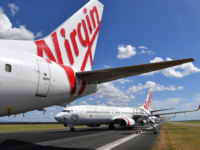 Grounded Virgin Australia aircraft are seen parked at Brisbane Airport in Brisbane, Tuesday, April 7, 2020. Brisbane Airport Corporation (BAC) is working with airlines by accommodating up to 100 grounded aircraft free of charge in response to government-mandated travel restrictions that have grounded a significant proportion of Australia's airline fleet because of the Coronavirus (COVID-19). (AAP Image/Darren England) NO ARCHIVING