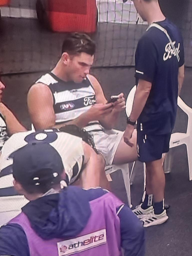 Tom Hawkins on the phone during the lightning break at the MCG on Monday.