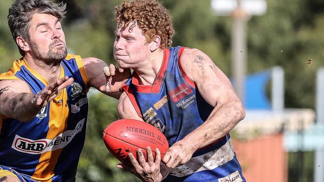 Gisborne's Flynn Lakey dishes off a handball under pressure from Golden Square opponent Hamish Morcom. Picture: SAA Imaging (supplied)