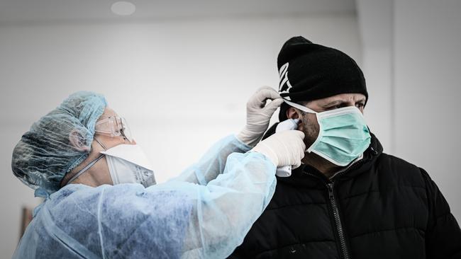 A staff member wearing a protective mask uses an ear thermometer at a medical centre in Paris.