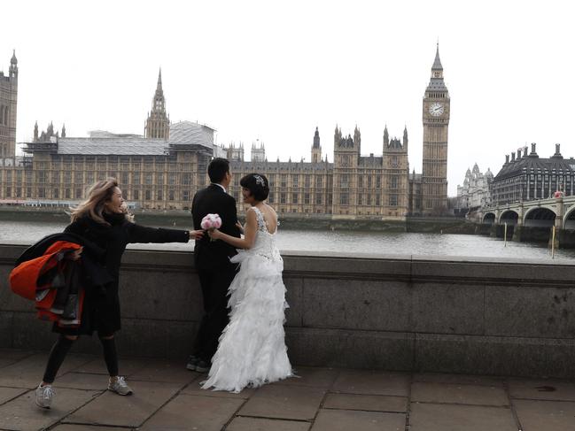 A couple prepare to pose for their wedding pictures by Westminster Bridge in central London on March 23, 2017 after the bridge reopened to traffic following its closure during the March 22 terror attack. Picture: AFP