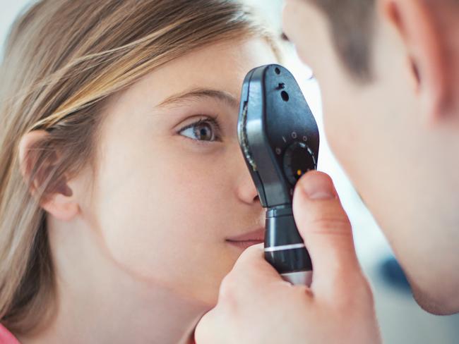 Closeup side view of early 40's unrecognizable optician examining eyesight of his little female patient with a phoropter device. The girls is aged 9, with brown eyes and hair. Picture: iStock