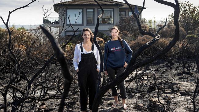 Bella Wolff (left) and her sister Claudia, with their home in the background, stand on the North Curl Curl headland after the hazard reduction burn-off. Picture: Julian Andrews