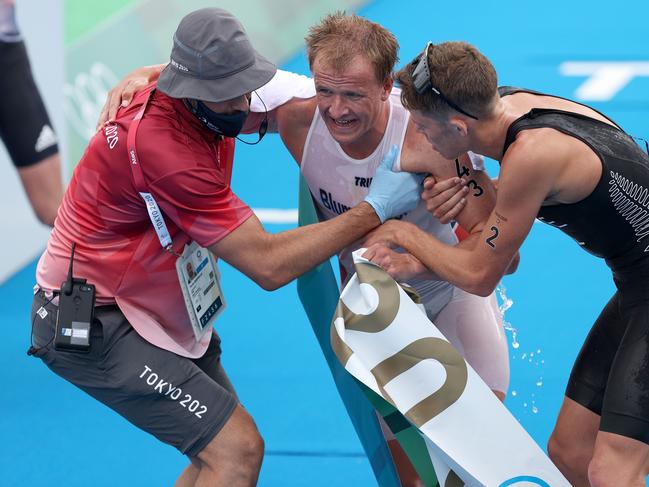 Kristian Blummenfelt is helped up by bronze medallist Hayden Wilde of Team New Zealand following the Men's Individual Triathlon. Picture: Getty Images