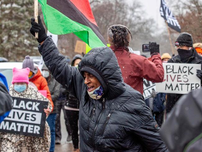 A protester chants as people hold Black Lives Matter signs during a demonstration against the police killing of Andre Hill in the neighborhood where Hill was shot, in Columbus, Ohio on December 24, 2020. - The killing of an unarmed African-American man by police in the US city of Columbus, Ohio sparked a fresh wave of outrage this week against racial injustice and police brutality in the country. Andre Maurice Hill, 47, was in the garage of a house on the night of December 21 when he was shot several times by a police officer who had been called to the scene for a minor incident. (Photo by STEPHEN ZENNER / AFP)