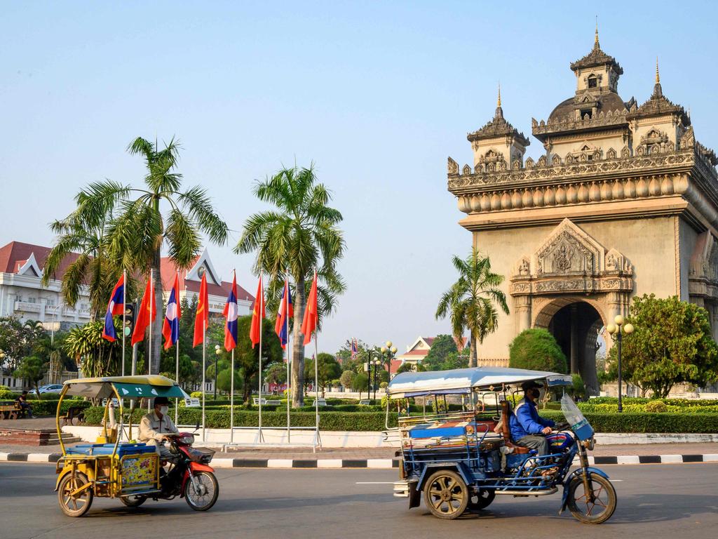 Traditional tuktuks passing in front of the Patuxai war monument in the centre of Vientiane. Laos has announced plans to partially re-open to foreign travellers in the new year. Picture: AFP