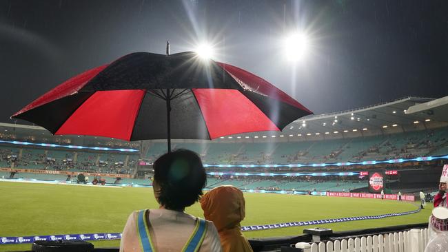 Spectators take shelter during a rain-affected BBL game in Sydney.