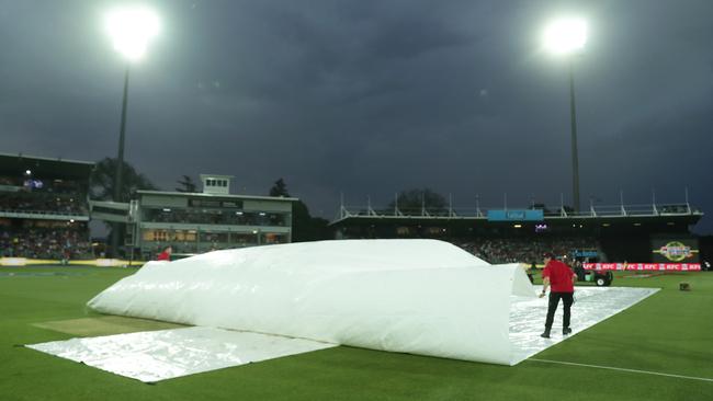 Ground staff cover the wicket during a rain delay in Launceston.