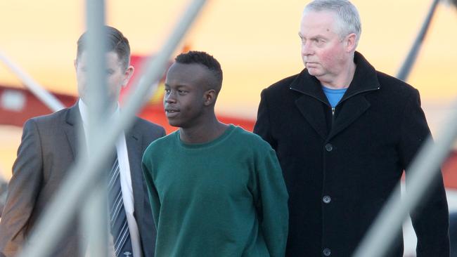 Christo Brown, centre, arriving back in Tasmania to face rape charges after a successful extradition application. 