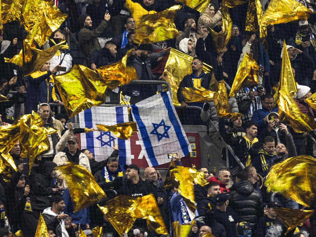 Maccabi supporters wave yellow flags next to Israeli flags during the UEFA Europa League.